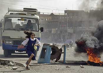 Una niña corre ante neumáticos en llamas que bloquean los accesos de la barriada bagdadí de Ciudad Sáder.rnrn  AP