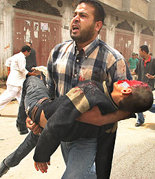 Un palestino traslada a un niño herido tras el ataque israelí a la manifestación, en el campo de Rafah.