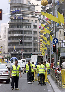 Varios operarios colocan vallas en la Gran Vía de Madrid.