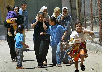 Mujeres y niños palestinos huyen de de la barriada de Brazil, en Rafah, ante los disparos de helicópteros israelíes.