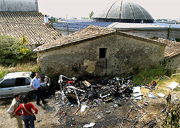 Investigadores de los Mossos d'Esquadra, junto a los restos de la caravana incendiada en Castell-Platja d'Aro.