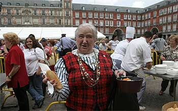 Una señora muestra su ración de cocido organizado en beneficio de la asociación Aldeas Infantiles SOS en la plaza Mayor.