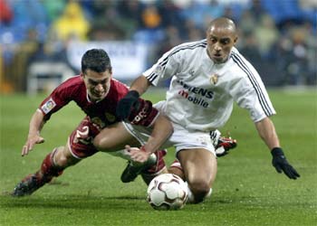 Roberto Carlos disputa el balón con el sevillista Casquero en un partido de Liga.