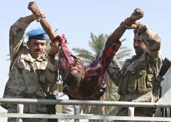 Dos militares iraquíes trasladan el cuerpo de una de las víctimas del atentado suicida cometido ayer en Bagdad.