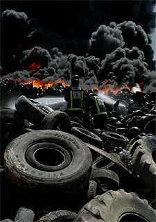 Los bomberos tratan de sofocar el fuego en los neumáticos.