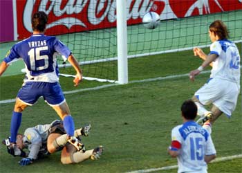 Vryzas trata de sortear al portero ruso, Malafeev, mientras observa cómo el balón, impulsado por él, entra en la portería en el tanto de Grecia.