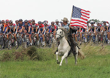 Un espectador, a caballo y con la bandera de Estados Unidos, anima el paso del pelotón.