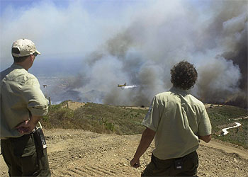 Dos hombres observan un avión que participaba ayer en la extinción del incendio.