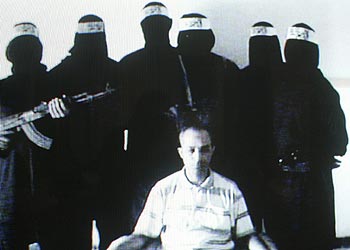 El egipcio Mohamed Mamdú Kutab aparece sentado delante de sus secuestradores en un vídeo emitido por Al Yazira.