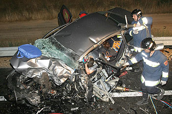 Los bomberos tratan de sacar del amasijo de hierros a uno de los fallecidos en el accidente.