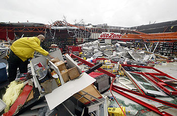 Un empleado de un gran almacén de repuestos de coche limpia el recinto, medio derruido tras el paso del huracán  Charley. 