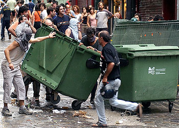 Un grupo de jóvenes cruza un contenedor en la calle durante los disturbios por el desalojo de un centro  okupa  en Pamplona.