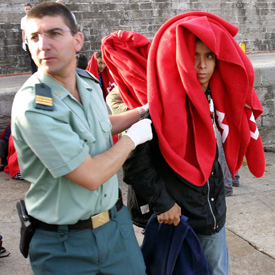 Un agente conduce a uno de los 40 magrebíes interceptados ayer en la costa de Tarifa.