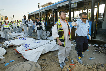 Policías y miembros de los servicios de socorro recuperan cadáveres tras la explosión de uno de los dos autobuses en Beersheva, al sur de Israel.