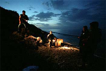 Un detenido, sentado encima de los fardos de hachís, en Torre del Mar (Málaga), tras una persecución de los agentes del SVA, en julio de 2003.
