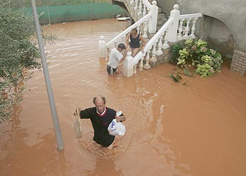 Una familia abandona su casa inundada en la playa de Nules (Castellón).