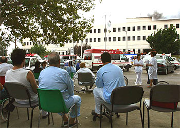 Varios pacientes esperan en el exterior del hospital a la extinción del fuego.