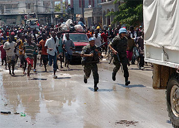 Un grupo de haitianos corre tras un camión con ayuda humanitaria mientras dos  cascos azules  tratan de protegerlo.