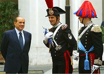 Berlusconi charla con dos  carabinieri  en traje de gala mientras espera a Abdalá de Jordania, en Roma.
