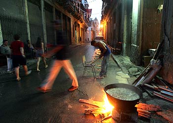 Transeúntes pasan junto a una olla de  caldosa,  un guiso típico cubano, en una calle de la Habana Vieja.