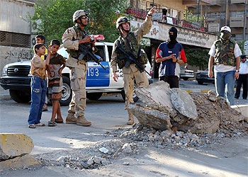 Soldados estadounidenses y policías iraquíes vigilan el lugar donde ayer explotó una bomba en Bagdad.rnrn.