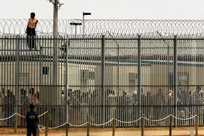 Un refugiado protesta desde la alambrada de un centro de detención de inmigrantes en Australia en abril de 2002.