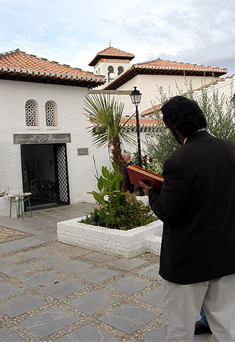 Un musulman en el jardín de la mezquita Mayor de Granada con un Corán en las manos.