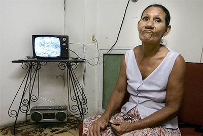 Una mujer cubana escucha el discurso en televisión del presidente Fidel Castro.