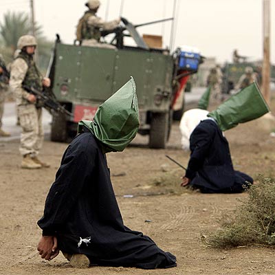 Una patrulla de  marines  norteamericanos vigila a dos iraquíes detenidos ayer en Abu Ghraib.