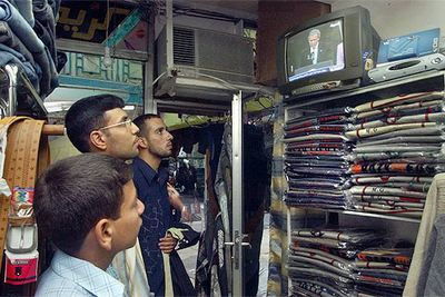 Tres empleados de una tienda de ropa de Bagdad siguen el discurso de Bush por la televisión.