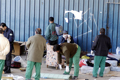 Inmigrantes acampados a las puertas del albergue de temporeros de Jaén recogen sus pertenencias tras la intervención policial de ayer.