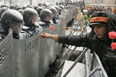 Una manifestante partidaria de Víktor Yúshenko ofrece claveles a los policías  antidisturbios  concentrados ante la sede presidencial.