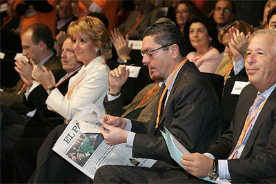 Esperanza Aguirre charla con el aún presidente del PP de Madrid, Pío García Escudero, mientras el alcalde, Alberto Ruiz-Gallardón, lee sentado.