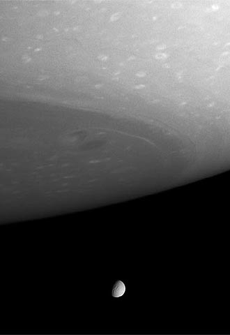 Fotografía de Saturno, en primer plano, con la luna Tetis al fondo.