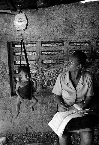 Una asistente sanitaria controla el peso de un niño en Mozambique.