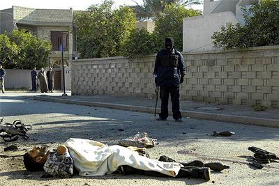 Un policía iraquí contempla el cadáver de un insurgente muerto ayer en una explosión en Bagdad.