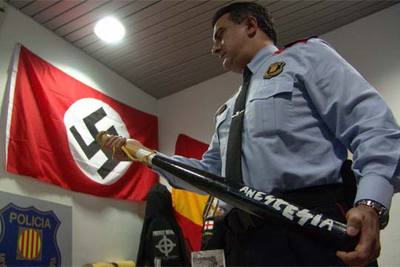 Un agente de la policía autonómica catalana muestra un bate de béisbol intervenido a una banda neonazi en Girona.