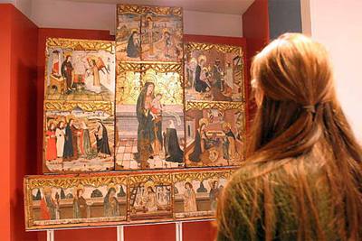 Una mujer contempla el retablo que se exhibe en el Museo de Isona.