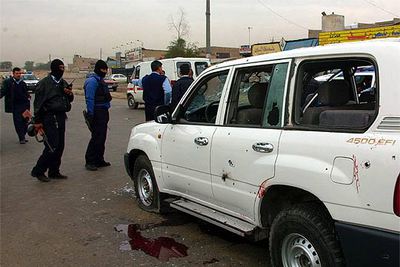 Miembros de las fuerzas de seguridad iraquíes observan el estado del vehículo en el que viajaban algunos de los escoltas del gobernador.