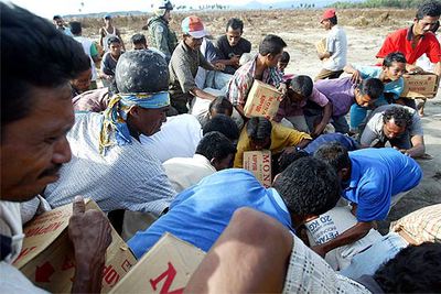 Supervivientes del maremoto recogen cajas con ayuda humanitaria en Banda Aceh (Indonesia).