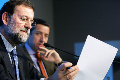 Mariano Rajoy, a la izquierda, junto a Eduardo Zaplana, lee un texto durante la rueda de prensa en la sede del PP.