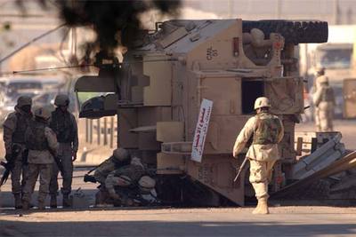 Soldados estadounidenses inspeccionan un blindado atacado ayer en el distrito bagdadí de Dora.