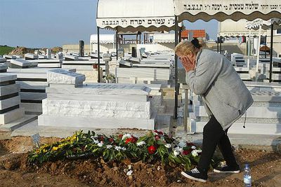 Una mujer llora ante la tumba de uno de los seis israelíes muertos en el atentado del jueves en Karni.