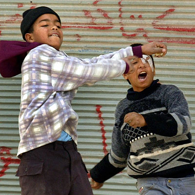 Dos niños palestinos lanzan piedras contra un vehículo israelí, ayer, durante unos disturbios en Nablús.