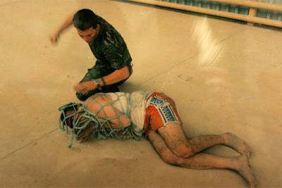 El cabo lancero Mark Cooley simula un puñetazo a un prisionero.