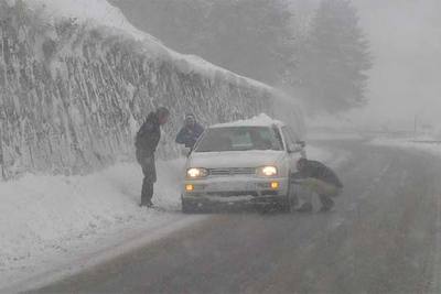 Un conductor se detiene para poner cadenas en su vehículo en la localidad de Vielha (Lleida).