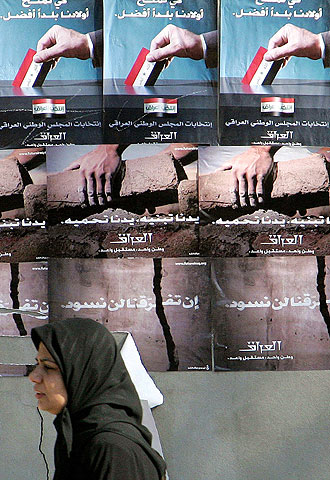 Una mujer iraquí pasa ante carteles electorales.