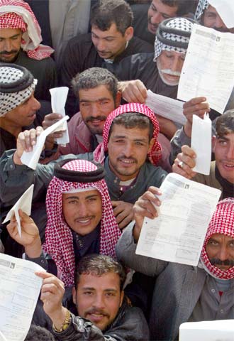 Varios iraquíes muestran sus documentos como votantes registrados ante un colegio en la ciudad santa de Nayaf.
