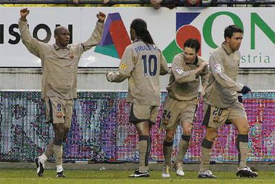 Samuel Eto'o celebra su gol bajo la lluvia y ante Ronaldinho mientras Iniesta y Deco se giran.