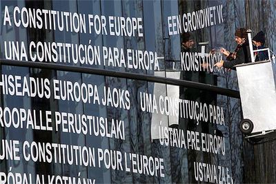 Dos trabajadores instalan un cartel en varios idiomas en la fachada del Parlamento Europeo.